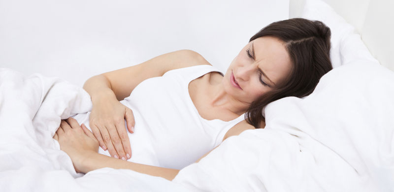 Woman In Bed Holding Her Stomach | Arkansas Talcum Powder Lawyer